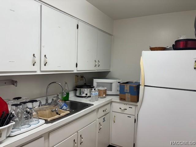 kitchen with sink, white cabinets, and white appliances