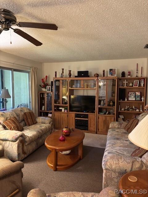 living room with ceiling fan, a textured ceiling, and carpet flooring