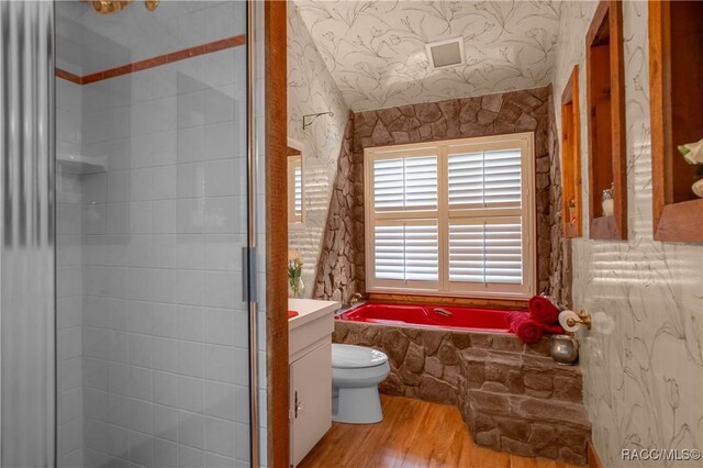 bathroom with a garden tub, toilet, a shower stall, vanity, and wood finished floors