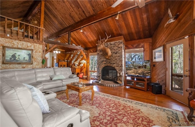 living room with lofted ceiling with beams, wood ceiling, and wooden walls