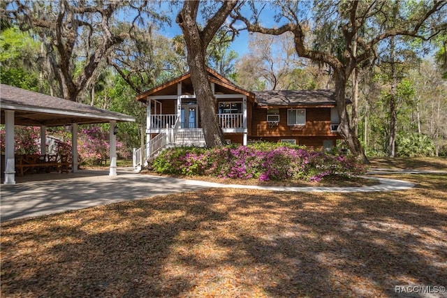 view of front facade with covered porch, concrete driveway, and stairs