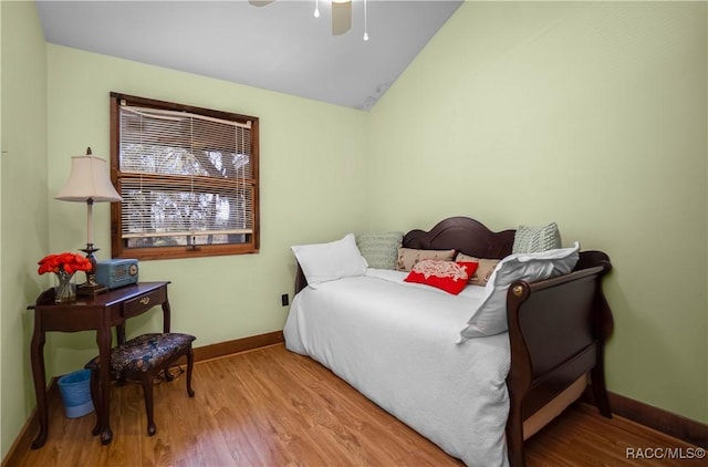 bedroom featuring lofted ceiling, wood finished floors, and baseboards