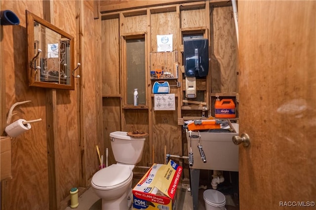 half bath with toilet and wood walls