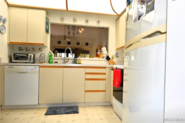 kitchen with cream cabinets, white dishwasher, and sink