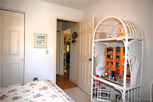 bedroom with a closet, wood-type flooring, and a textured ceiling