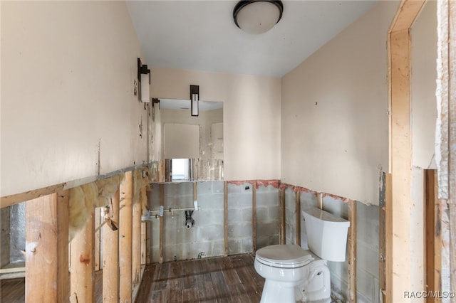 bathroom featuring toilet, wood-type flooring, and tile walls