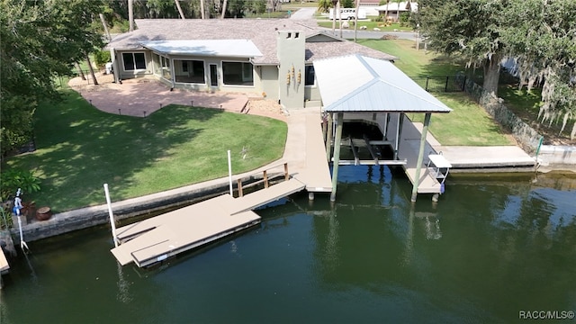 view of dock with a patio area, a water view, and a yard