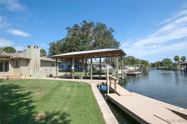 view of dock with a lawn and a water view