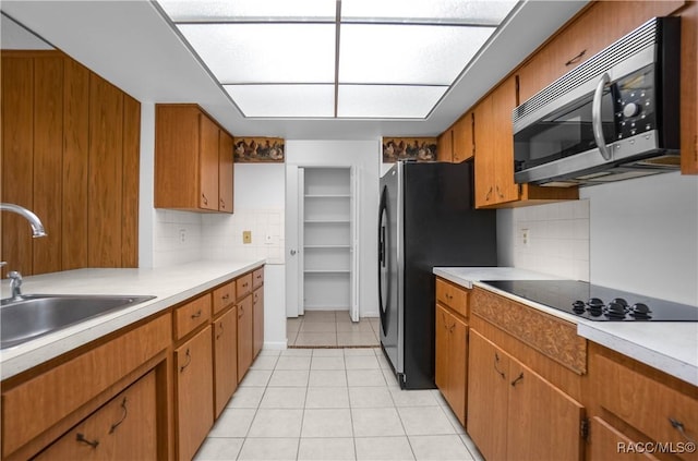 kitchen with tasteful backsplash, appliances with stainless steel finishes, sink, and light tile patterned floors