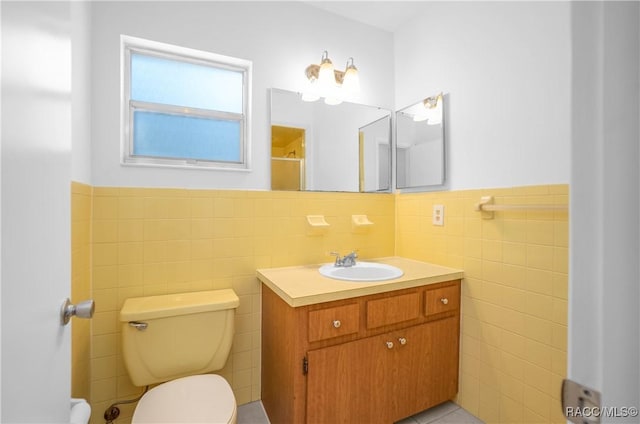 bathroom featuring vanity, toilet, and tile walls