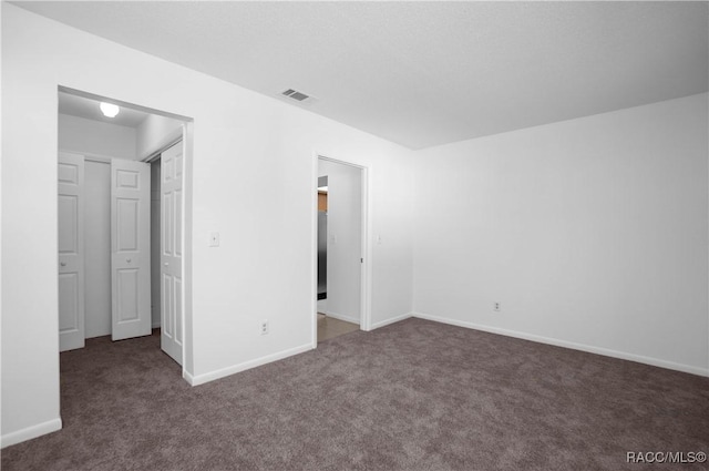 unfurnished bedroom with dark carpet and a closet