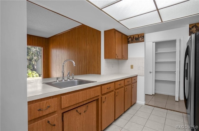 kitchen featuring light tile patterned flooring, fridge, sink, and decorative backsplash