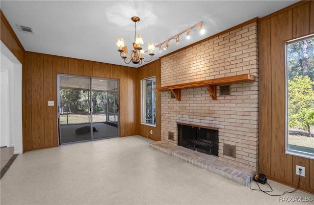 unfurnished living room with plenty of natural light, wooden walls, and a brick fireplace