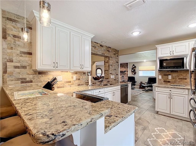 kitchen featuring kitchen peninsula, a kitchen bar, decorative light fixtures, and white cabinetry