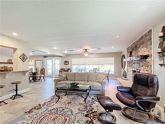 living room with a fireplace, a textured ceiling, and ceiling fan