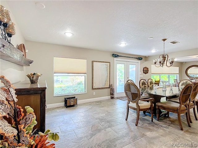 dining space featuring french doors, a healthy amount of sunlight, a textured ceiling, and an inviting chandelier