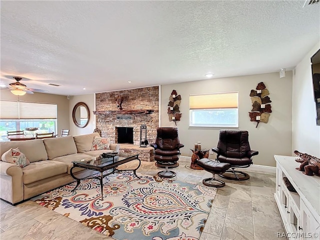 living room with a fireplace, a textured ceiling, ceiling fan, and a healthy amount of sunlight