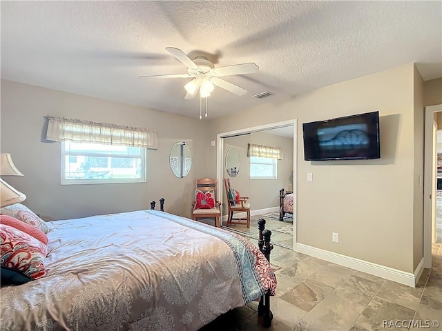 bedroom with a textured ceiling, ceiling fan, multiple windows, and a closet