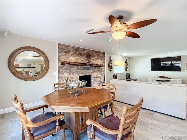 dining room featuring ceiling fan and a fireplace