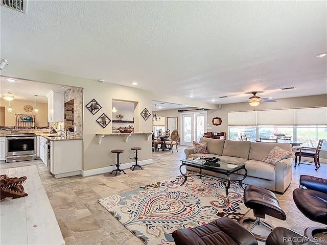 living room featuring a textured ceiling, ceiling fan, and sink