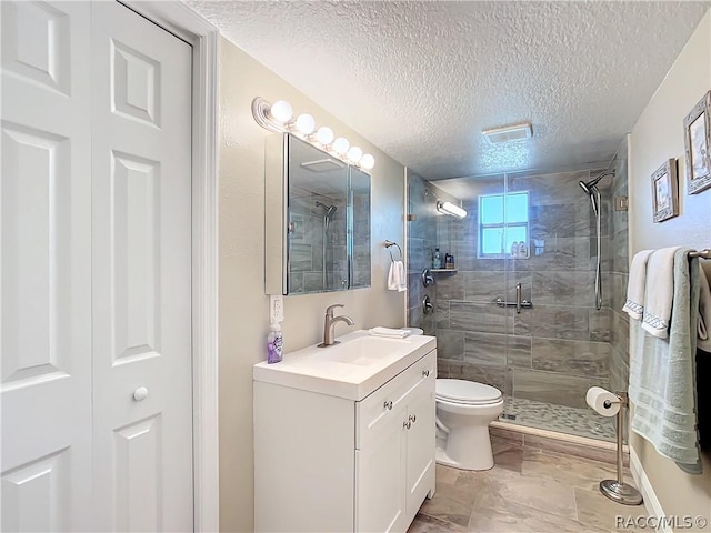 bathroom featuring vanity, toilet, a shower with door, and a textured ceiling