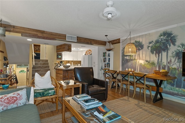 living room with beamed ceiling, a textured ceiling, and hardwood / wood-style flooring