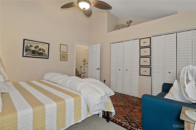 bedroom with carpet, high vaulted ceiling, ceiling fan, and multiple closets