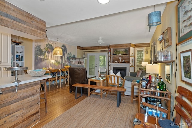 dining room with french doors, a large fireplace, light hardwood / wood-style floors, and vaulted ceiling