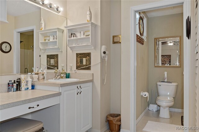 bathroom featuring tile patterned flooring, vanity, toilet, and a shower