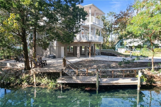 rear view of property with a patio area, a balcony, and a water view