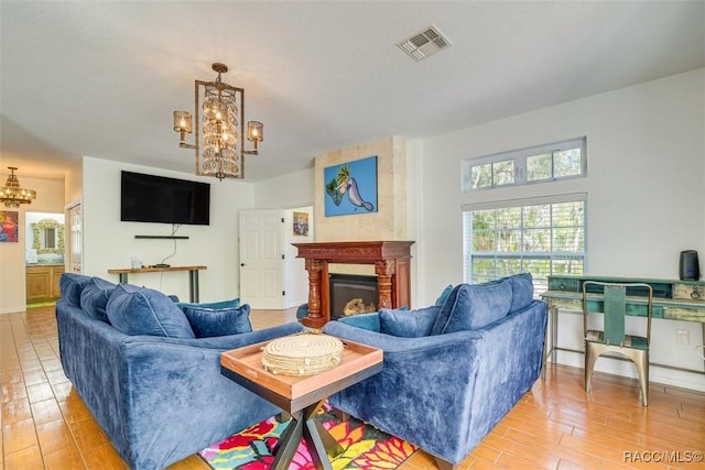 living room featuring a chandelier, a large fireplace, and light hardwood / wood-style floors