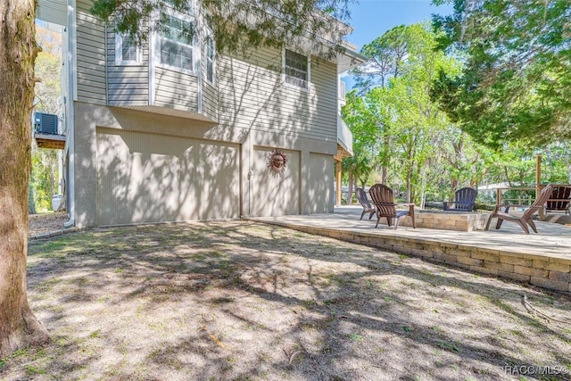 rear view of property with a patio, central AC unit, and a garage