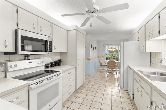 kitchen featuring backsplash, white appliances, sink, light tile patterned floors, and white cabinets