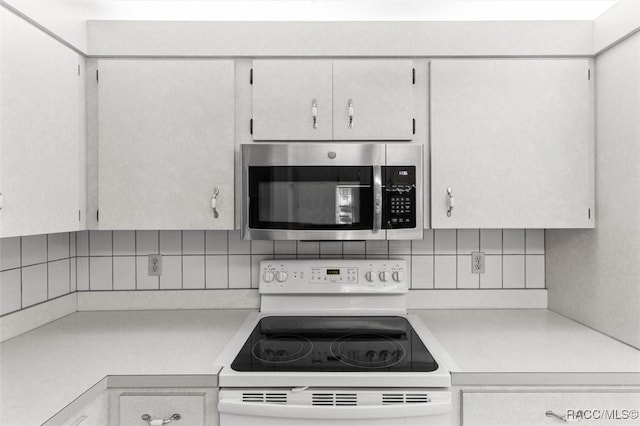 25 Redbay Ct W, Homosassa, FL 34446 - kitchen featuring stainless steel microwave, white electric stove, light countertops, and decorative backsplash