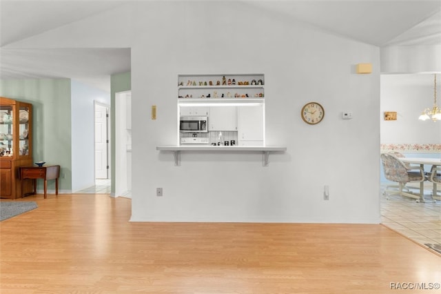 living room with light hardwood / wood-style floors, lofted ceiling, and a notable chandelier