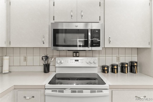 kitchen featuring white electric range oven, white cabinetry, and backsplash