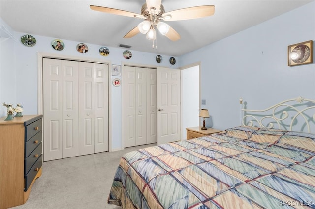 bedroom with multiple closets, ceiling fan, and light colored carpet