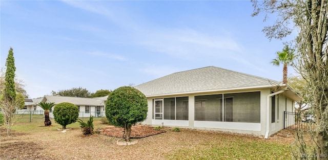 back of house featuring a shingled roof, fence, and a sunroom