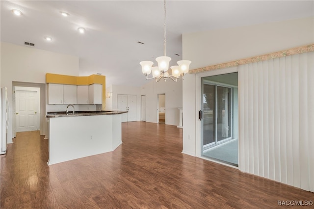 kitchen featuring dark wood-style floors, decorative light fixtures, dark countertops, visible vents, and a sink