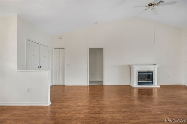 unfurnished living room featuring high vaulted ceiling, a ceiling fan, wood finished floors, and a glass covered fireplace