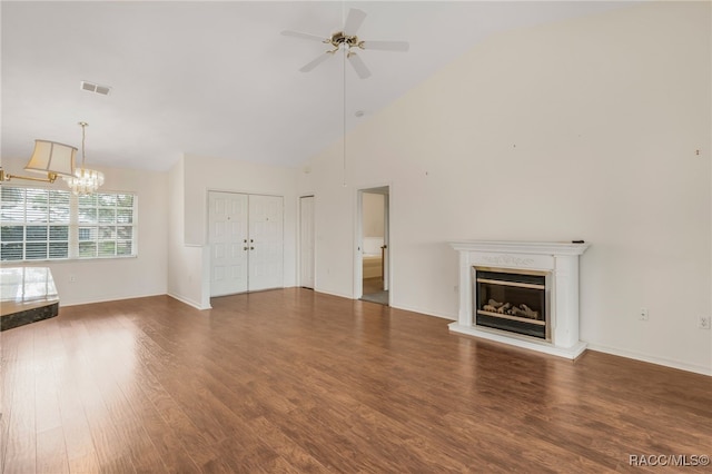 unfurnished living room with ceiling fan with notable chandelier, high vaulted ceiling, wood finished floors, and a glass covered fireplace