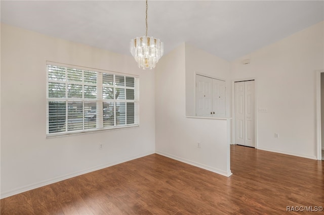 unfurnished room with vaulted ceiling, baseboards, wood finished floors, and an inviting chandelier