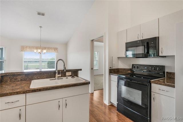 kitchen featuring a sink, visible vents, black appliances, dark countertops, and decorative light fixtures