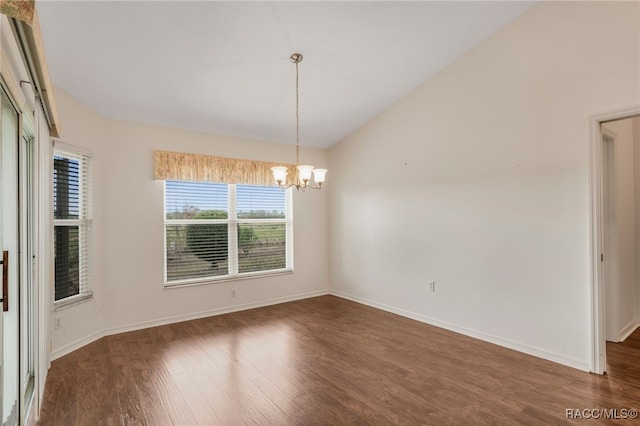 spare room featuring a chandelier, lofted ceiling, dark wood finished floors, and baseboards