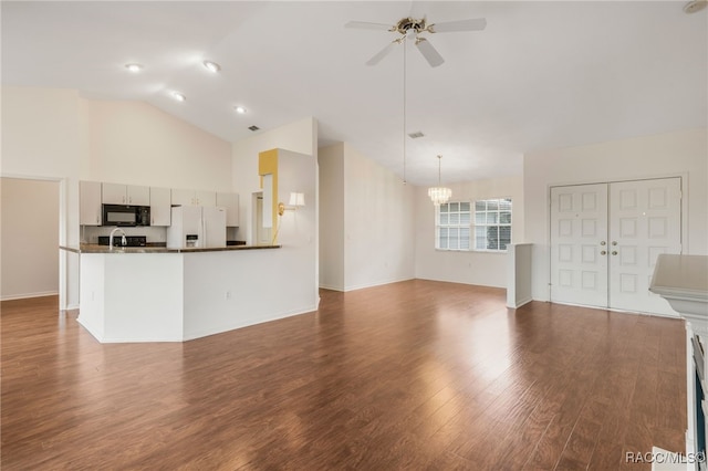 unfurnished living room with baseboards, wood finished floors, high vaulted ceiling, a sink, and ceiling fan with notable chandelier