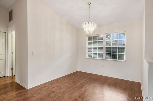 unfurnished room featuring an inviting chandelier, baseboards, visible vents, and wood finished floors