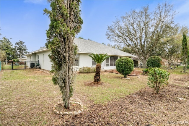 view of side of property featuring stucco siding, fence, and a yard