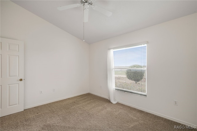 carpeted spare room with a ceiling fan, vaulted ceiling, and baseboards