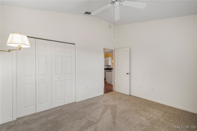 unfurnished bedroom featuring carpet flooring, visible vents, baseboards, vaulted ceiling, and a closet