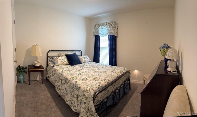 bedroom with dark colored carpet and baseboards